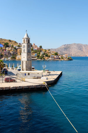 Clock tower on Symi island and view of the sea bay. Dodecanese islands, Greece
