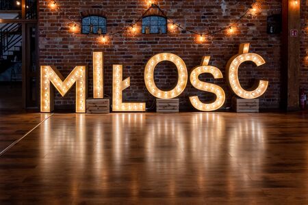Wedding Milosc sign in Polish language (Love in English). Large letters lighting with bulb lights. Poland, Europeの写真素材