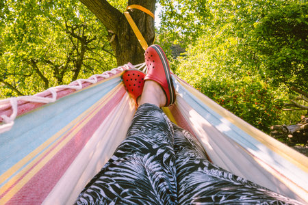 Female legs on a hammock in the garden. Leisure in summer