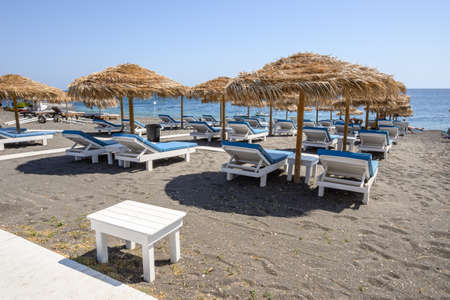 Santorini, Greece - September 17, 2020: Sun loungers on the black volcanic sand beach of Perissa on the island of Santorini. Cyclades, Greeceのeditorial素材