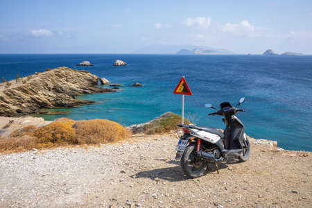Folegandros, Greece - September 24, 2020: Scooter parked on rocky coast on the island of Folegandros. A scooter is a popular means of transport in Greece.のeditorial素材