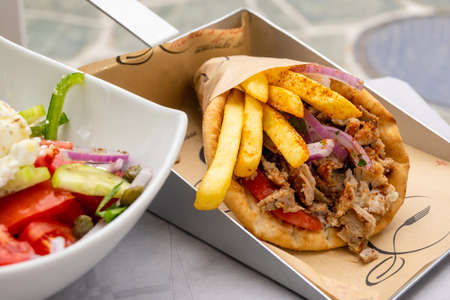 Folegandros, Greece - September 24, 2020: Traditional Greek souvlaki with chicken gyros, vegetables and fries served in pita bread.のeditorial素材