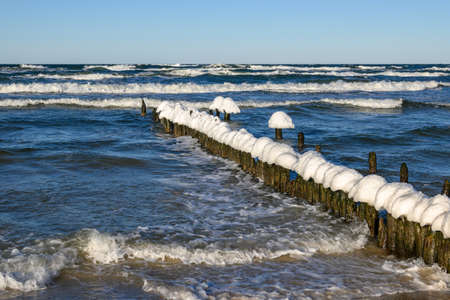 Snow caps on wooden stakes at the Baltic Sea during winter. Debki, Polandの写真素材