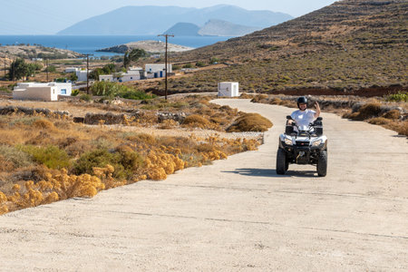 Folegandros, Greece - September 25, 2020: Man driving a quad on the road on Folegandros island. Quad is very popular means of transport in Greece. Cyclades Islandsのeditorial素材