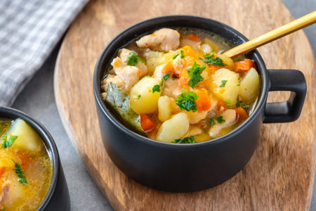 Chicken stew with potatoes, zucchini, and carrots in a bowlの写真素材