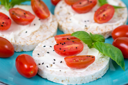 Rice cake sandwich with cheese cream, tomato, basil and spices. A healthy dietary snack