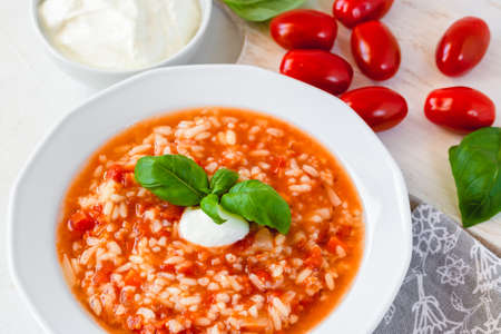 Tomato soup with rice decorated by cream and basil leaf.の写真素材