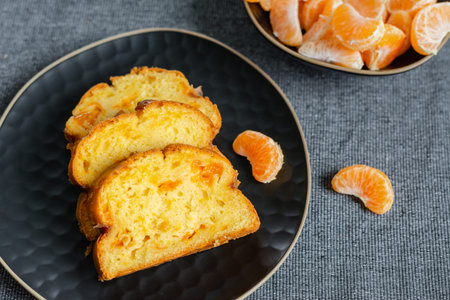 Homemade mandarin cake and tangerine on a plate.