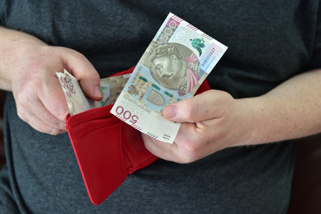 Hands holding wallet with polish currency money. Concept of financial security in old age during...
