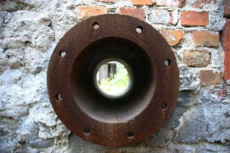 rusted pipe flange mounted on a red brick and concrete wallの写真素材