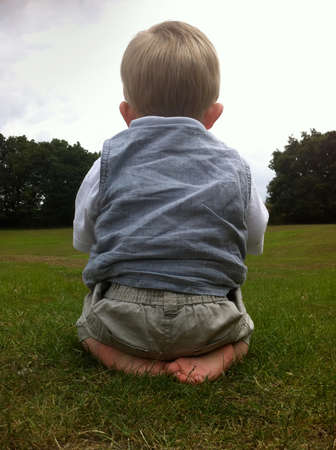 Cute baby boy sat alone in park, sadの写真素材