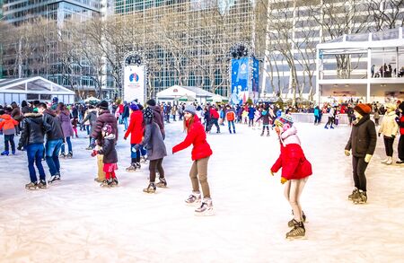 New York City, NY / USA - 12 23 2013: People are enjoying ice skating at Bryant park Midtown Manhattan in front of the New York Public library with a Christmas tree during Christmas holiday season.のeditorial素材
