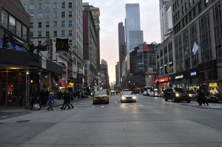 New York City, NY / USA - 12 25 2013: New York City downtown Manhattan busy street with people, tourists crossing, yellow taxi cabs, and cars. Crossing road in busy city downtown at sunset.のeditorial素材