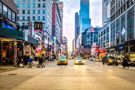 New York City, NY / USA - 12 25 2013: New York City downtown Manhattan busy street with people, tourists crossing, yellow taxi cabs, and cars. Crossing road in busy city downtown at sunset.のeditorial素材