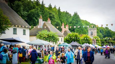 Milton Abbas / UK - July 29 2017: People are walking down the street in Milton Abbas village, Dorset during the 18th-century? street fair. English traditional medieval fair / market countryside.のeditorial素材