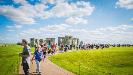 Salisbury, Wiltshire / UK - 08 25 2017: People, visitors walking on the road towards Stonehenge world heritage site in green countryside landscape. Summer holidays destination in the UK, Europe.のeditorial素材