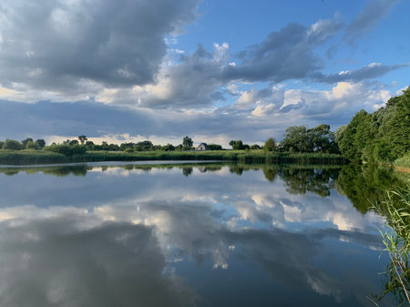Reflection of clouds in the water of a lake on a summer dayの写真素材
