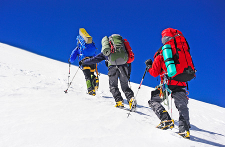 Two mountain backpackers walking on snowの写真素材