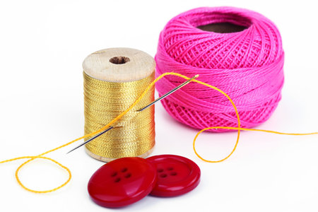 Colored thread, needles and buttons on a white background 