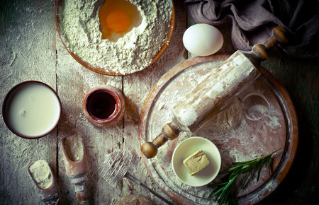 Dough with flour on an old background in a composition with kitchen accessoriesの写真素材