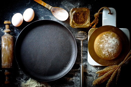 Dough with flour on an old background in a composition with kitchen accessoriesの写真素材