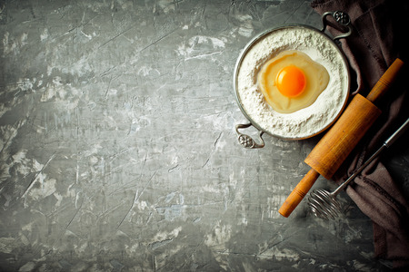 Dough with flour on an old background in a composition with kitchen accessoriesの写真素材