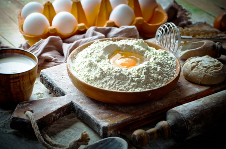 Dough with flour on an old background in a composition with kitchen accessoriesの写真素材