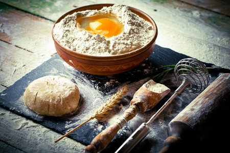 Dough with flour on an old background in a composition with kitchen accessoriesの写真素材