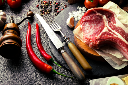 Raw meat on the kitchen table on a metallic background in a composition with cooking accessoriesの写真素材