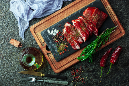 Raw meat on the kitchen table on a metallic background in a composition with cooking accessoriesの写真素材