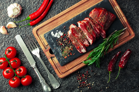 Raw meat on the kitchen table on a metallic background in a composition with cooking accessoriesの写真素材