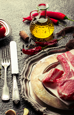 Raw meat on the kitchen table on a metallic background in a composition with cooking accessoriesの写真素材
