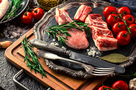 Raw meat on the kitchen table on a metallic background in a composition with cooking accessoriesの写真素材