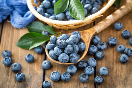 Fresh ripe blueberries in a wooden spoon on a wooden table.の写真素材