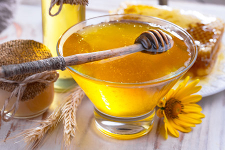 Honey in a glass bowl with honey dipper and honeycombsの写真素材