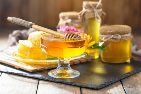 Honey in a glass jar and honeycomb on a wooden backgroundの写真素材
