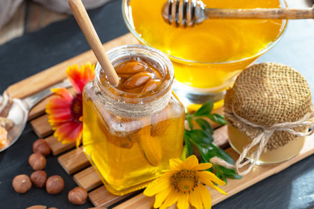 Honey in a glass jar with wooden drizzler and honeycomb on a wooden backgroundの写真素材