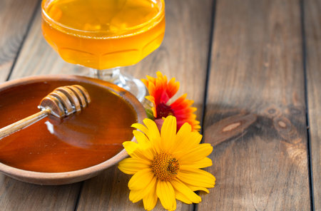 Honey in a glass bowl and honey dipper on a wooden backgroundの写真素材