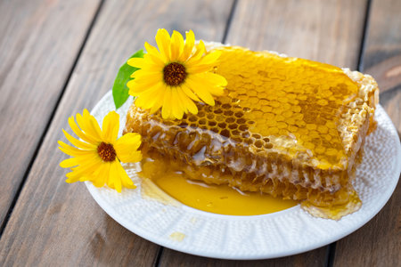 Honeycombs with honey and yellow flowers on a wooden backgroundの写真素材