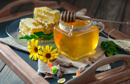 Honey in a glass jar and honeycombs on a wooden backgroundの写真素材
