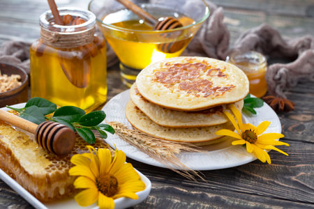 Homemade pancakes with honey and wildflowers on a wooden backgroundの写真素材