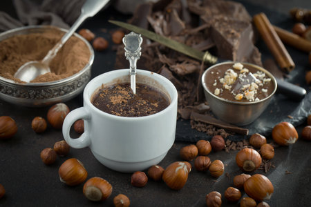 Cup of hot chocolate with hazelnuts and chocolate pieces on dark backgroundの写真素材