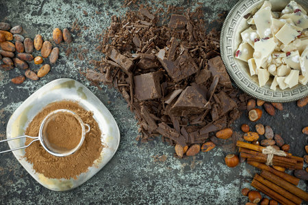 Cocoa powder, chocolate pieces and cocoa beans on dark background