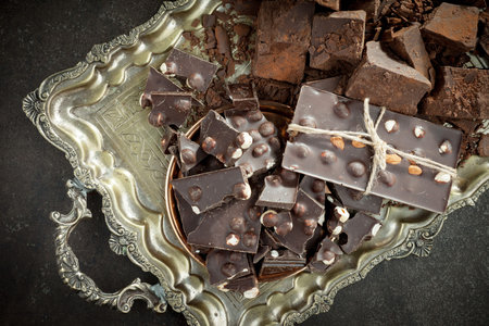 Pieces of dark chocolate with hazelnuts on a metal tray