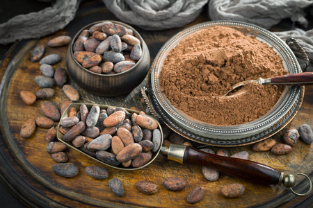Cocoa powder in a bowl and raw cocoa beans on an old background.の写真素材