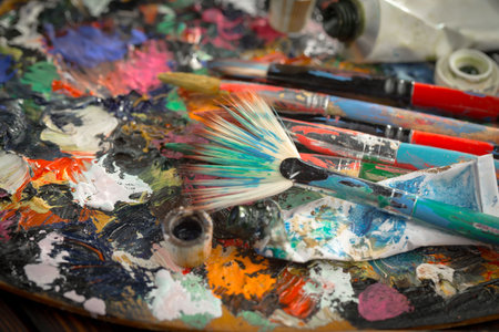 Paint brushes and palette with paints on wooden table, closeupの写真素材