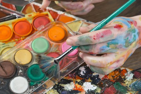 Close-up of artist's hands with paint brushes and palette of colorsの写真素材