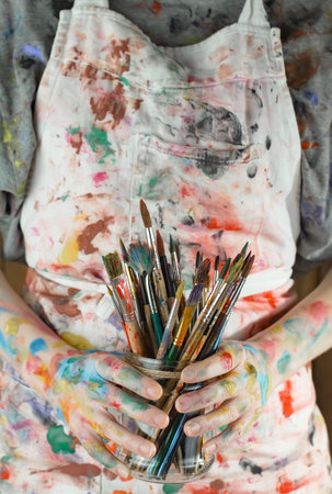 Female artist with paintbrushes in her hands. Close-up.の写真素材