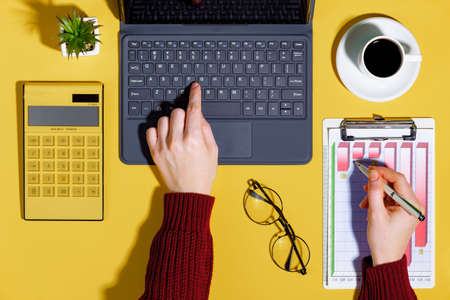 Female hands with items for doing business on a bright colored backgroundの写真素材
