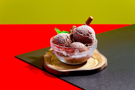 Chocolate ice cream in a glass bowl on a red and green background